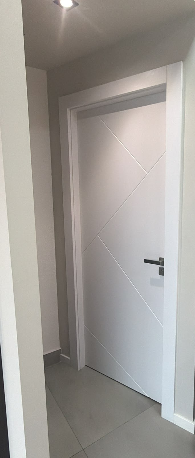 Porta branca com frisos diagonais decorativos e puxador preto