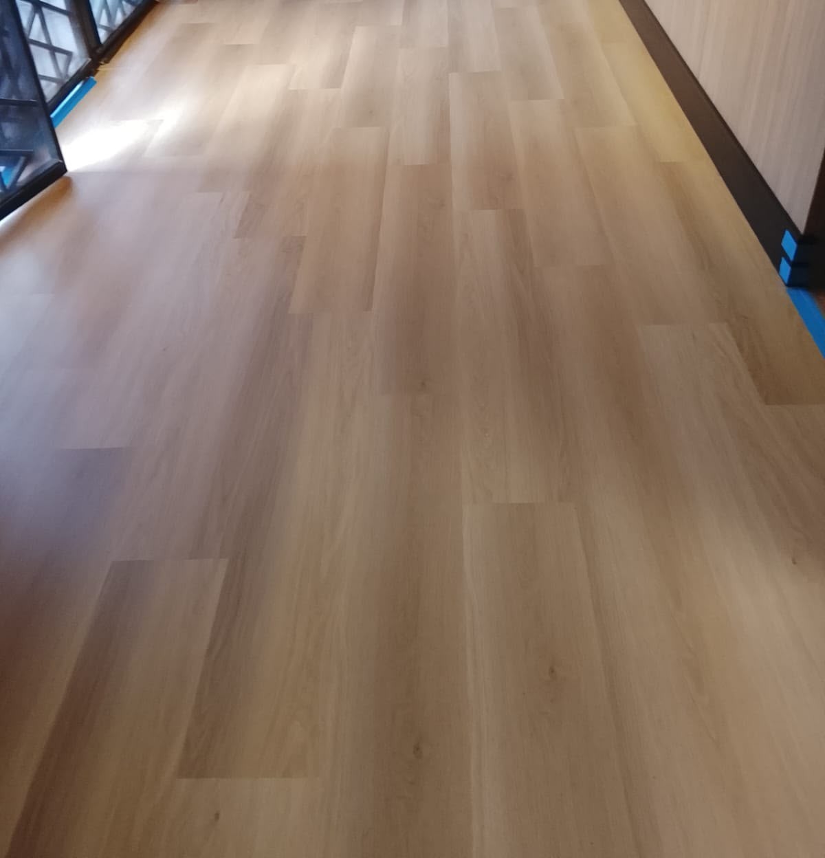 Piso amadeirado claro recém-instalado com rodapé preto