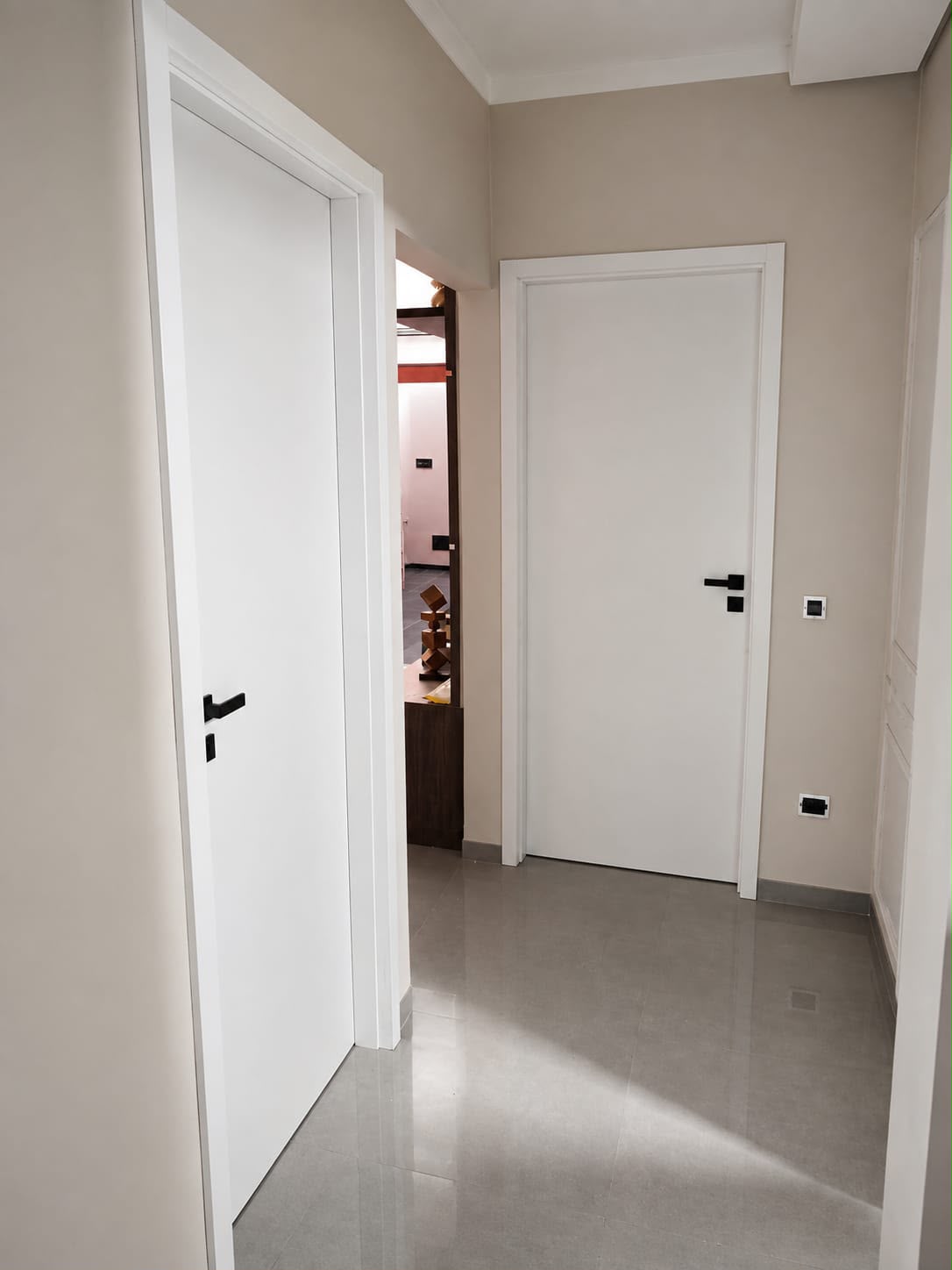 Duas portas brancas com puxadores pretos em um corredor